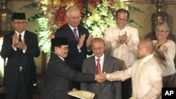 Government peace negotiator Marvic Leonen (R) and Moro Islamic Liberation Front chief negotiator Mohagher Iqbal (L) shake hands following a formal signing ceremony in Manila, Philippines, October 15, 2012.
