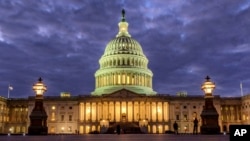 FILE - Lights shine inside the U.S. Capitol Building as night falls in Washington, Jan. 21, 2018.