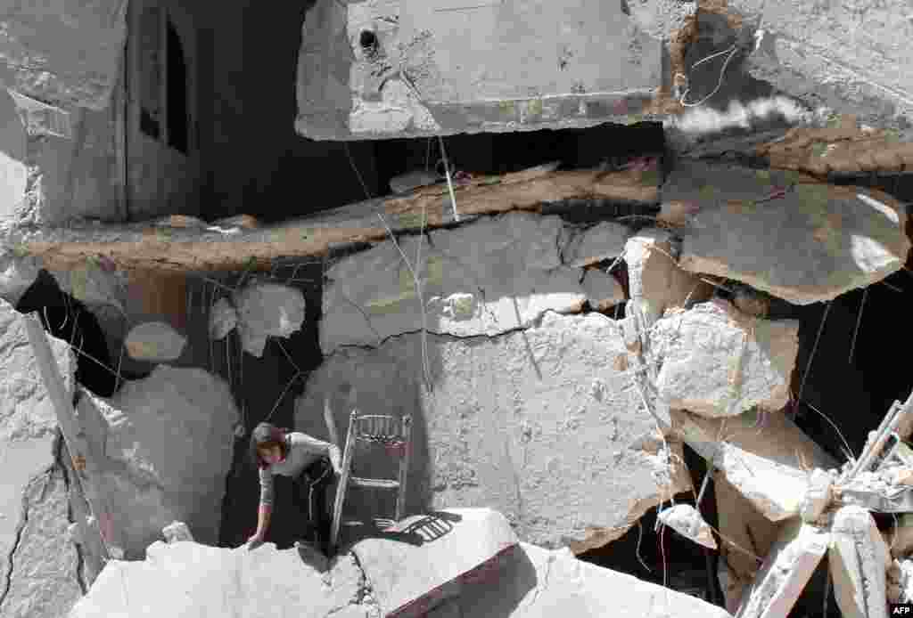 A Syrian girl collects her belongings from rubble after her building was destroyed in an air strike reportedly by government forces in the northern city of Aleppo.