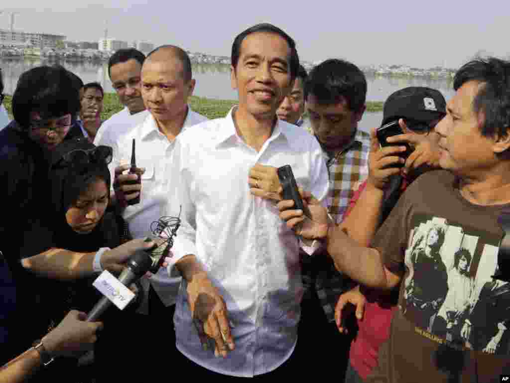 Kandidat presiden Indonesia Joko Widodo berbicara dengan media dalam kunjungan ke Waduk Pluit menjelang pengumuman hasil pemilihan presiden 2014 (22/7). (AP/Dita Alangkara)