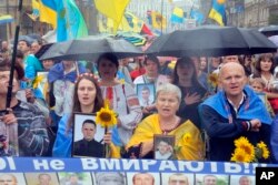 FILE - People hold photos of Ukrainian soldiers killed in the conflict with Russia-backed separatists in Ukraine's east, at a rally in Kyiv, Aug. 24, 2016. Many Ukrainians view the presence of Russian dissidents in Ukraine with distrust, with some saying they should organize in Russia.