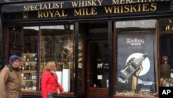 FILE A man and a woman pass a whisky shop on the 'Royal mile' in Edinburgh, Scotland.