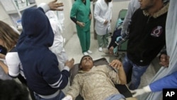 A wounded man is carried into the al-Jala hospital in Benghazi after an attack by Libyan military forces loyal to Muammar Gaddafi on a weapons dump near Benghazi in rebel-controlled eastern Libya killed 17 people.