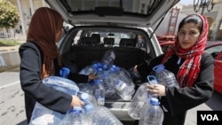 Para perempuan muslim ikut menjadi sukarelawan membagi-bagikan air bersih yang menjadi barang langka di ibukota Tripoli (29/8).