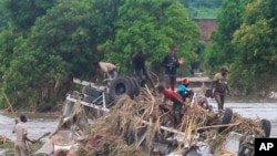 In this still image from video, people stand on an overturned vehicle that was swept away by floodwaters, in Chikwawa, Malawi, Jan. 25, 2022. 