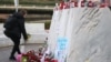 Una mujer coloca flores en la estatua del difunto Papa Juan Pablo II afuera del Hospital Gemelli, donde el Papa Francisco está ingresado para recibir tratamiento, en Roma, Italia, el 28 de febrero de 2025.