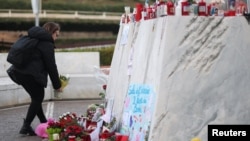 Una mujer coloca flores en la estatua del difunto Papa Juan Pablo II afuera del Hospital Gemelli, donde el Papa Francisco está ingresado para recibir tratamiento, en Roma, Italia, el 28 de febrero de 2025.