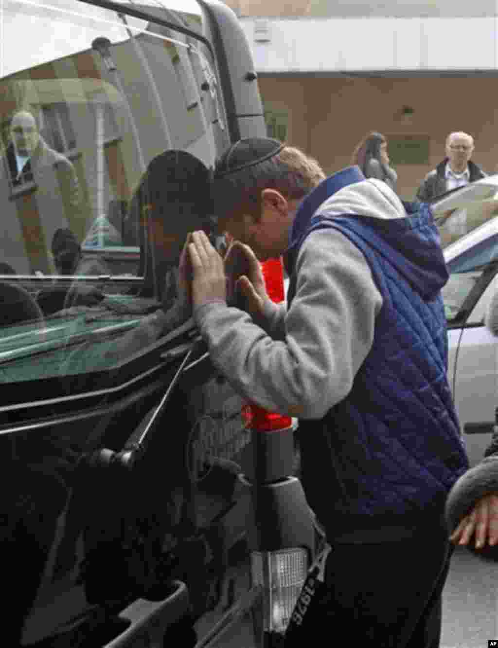 A youngster cries against a hearse, following a ceremony at the Ozar Hatorah Jewish school where a gunman opened fire killing four people in Toulouse, southwestern France, Tuesday, March 20, 2012. A father and his two sons were among four people who died 