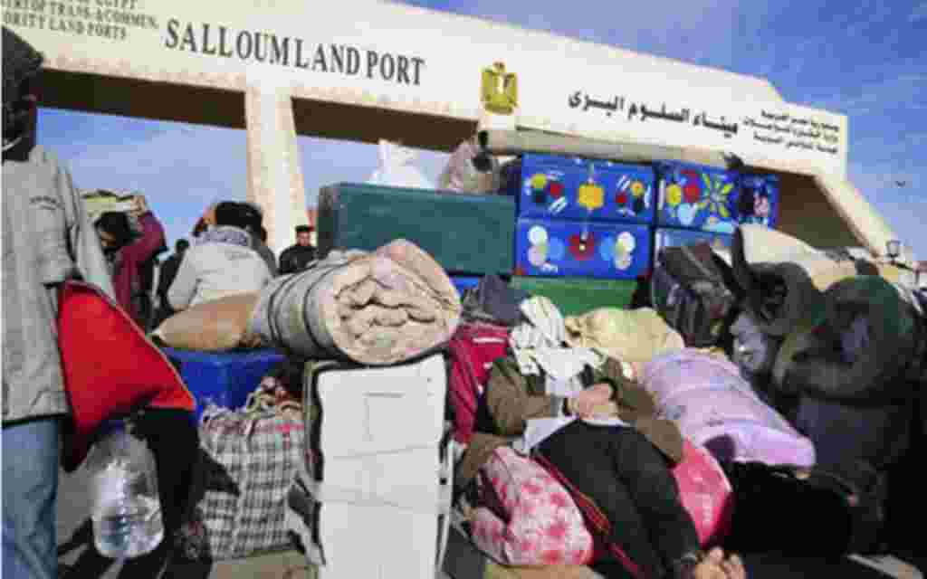 An Egyptian, who has just crossed Salloum land port gate with Libya, at background, takes a nap over his luggage. Thousands of other foreigners were still stranded, February 23, 2011
