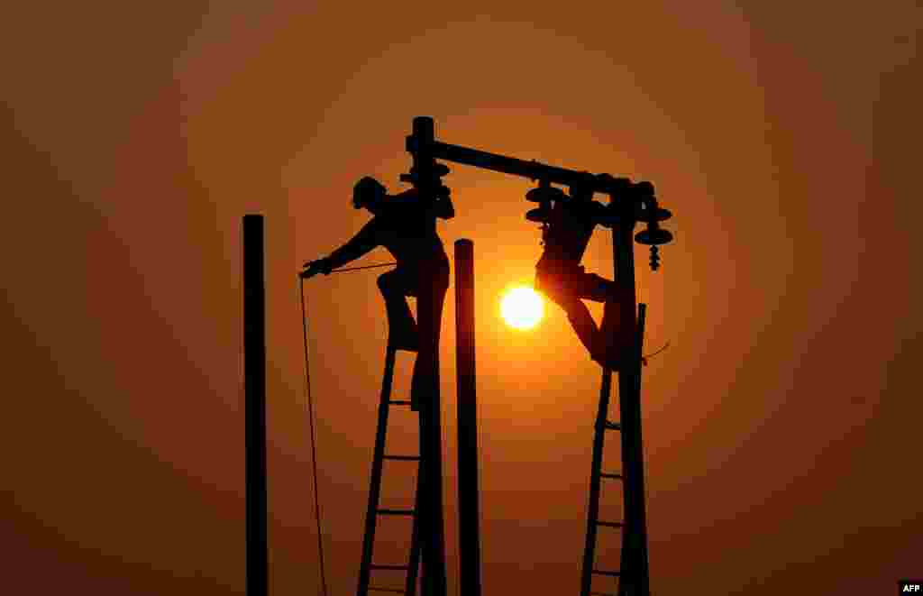 Indian electricians adjust electric cables set up temporarily on the banks of the river Ganga in preparation for the annual Hindu religious fair of Magh Mela in Allahabad.