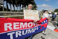 FILE - Ray Bonachea holds a sign in favor of the impeachment of President Donald Trump, outside the Trump National Doral Miami golf resort, Dec. 17, 2019, in Doral, Fla.