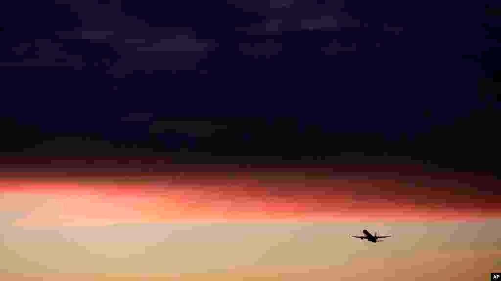 A plane takes off from the Los Angeles International Airport as clouds reflect the color of the sunset in Los Angeles, California, Dec. 2, 2013.