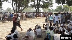 Onlookers sit at the site where two girls were hanged from a tree at Badaun district in the northern Indian state of Uttar Pradesh, May 28, 2014.