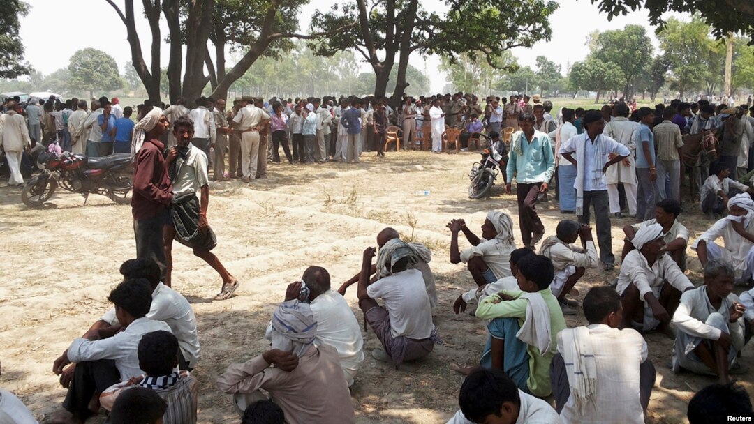 Warga Badaun, Uttar Pradesh, India utara berkumpul di lokasi di mana dua remaja perempuan korban perkosaan tewas dengan menggantung diri di pohon (28/5).