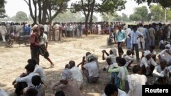 Warga Badaun, Uttar Pradesh, India utara berkumpul di lokasi di mana dua remaja perempuan korban perkosaan tewas dengan menggantung diri di pohon (28/5).