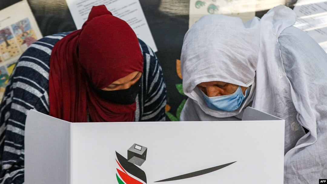 Seorang pemilih mencentang surat suaranya di belakang layar privasi di TPS kamp al-Baqaa untuk pengungsi Palestina, di utara ibu kota Yordania, 10 November 2020. (Foto:Khalil MAZRAAWI / AFP)