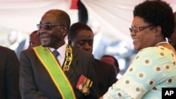 FILE: Zimbabwean President Robert Mugabe reacts with his deputy Joice Mujuru, during Defence Forces Day in Harare, Tuesday, Aug. 14, 2012.
