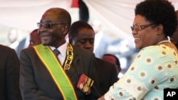 FILE: Zimbabwean President Robert Mugabe reacts with his deputy Joice Mujuru, during Defence Forces Day in Harare, Tuesday, Aug. 14, 2012.