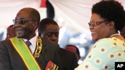 FILE: Zimbabwean President Robert Mugabe reacts with his deputy Joice Mujuru, during Defence Forces Day in Harare, Tuesday, Aug. 14, 2012.