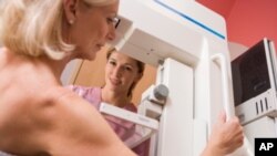 A nurse is seen assisting a patient undergoing a mammogram.