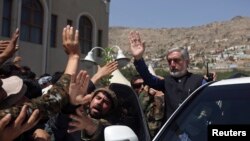 Afghan presidential candidate Abdullah Abdullah (R) waves after a ceremony commemorating the 2001 assassination of legendary Tajik resistance commander Ahmad Shah Massoud, in Kabul, September 9, 2014.