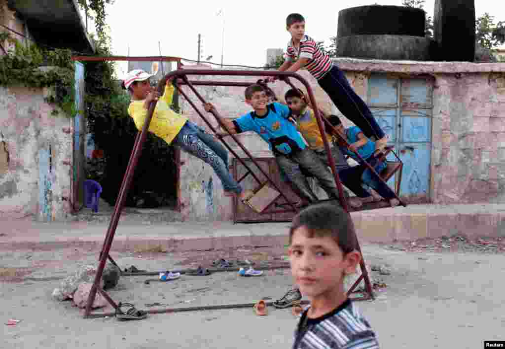 Trẻ em, trong trung t&acirc;m th&agrave;nh phố Aleppo, vui đ&ugrave;a tr&ecirc;n chiếc x&iacute;ch đu