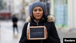 FILE - Malika Etchekopar-Etchart, unemployed, holds a blackboard with the word "chomage" (unemployment), the most important election issue for her, as she poses for Reuters in Chartres, France.