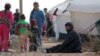 FILE - Iraqi refugees rest near tents in an Iraqi refugee camp in the village of Mabrouka, western countryside of Ras al-Ain, Syria, Jan. 31, 2016. 