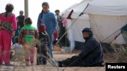 FILE - Iraqi refugees rest near tents in an Iraqi refugee camp in the village of Mabrouka, western countryside of Ras al-Ain, Syria, Jan. 31, 2016. 