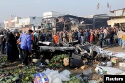 FILE - People gather at the site of a car bomb attack at a vegetable market in eastern Baghdad, Jan. 8, 2017.