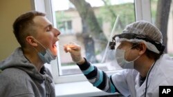 A medical worker takes swabs for the coronavirus test from a conscript during a medical checkup at a military conscription office in Moscow, Russia, May 22, 2020. 