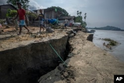 Villagers walk past an eroding bank by the river Brahmaputra at Murkata village, India, Sunday, Oct. 9, 2022.