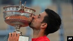 FILE - Serbia's Novak Djokovic kisses the cup after defeating Stefanos Tsitsipas of Greece during their final match of the French Open tennis tournament at the Roland Garros stadium, June 13, 2021 in Paris.