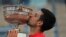FILE - Serbia's Novak Djokovic kisses the cup after defeating Stefanos Tsitsipas of Greece during their final match of the French Open tennis tournament at the Roland Garros stadium, June 13, 2021 in Paris.