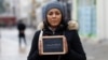 FILE - Malika Etchekopar-Etchart, unemployed, holds a blackboard with the word "chomage" (unemployment), the most important election issue for her, as she poses for Reuters in Chartres, France.