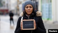 FILE - Malika Etchekopar-Etchart, unemployed, holds a blackboard with the word "chomage" (unemployment), the most important election issue for her, as she poses for Reuters in Chartres, France.