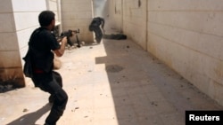 FILE - A Free Syrian Army (FSA) fighter (L) provides cover for his fellow fighter during an offensive to seize Aleppo's town of Khanasir.