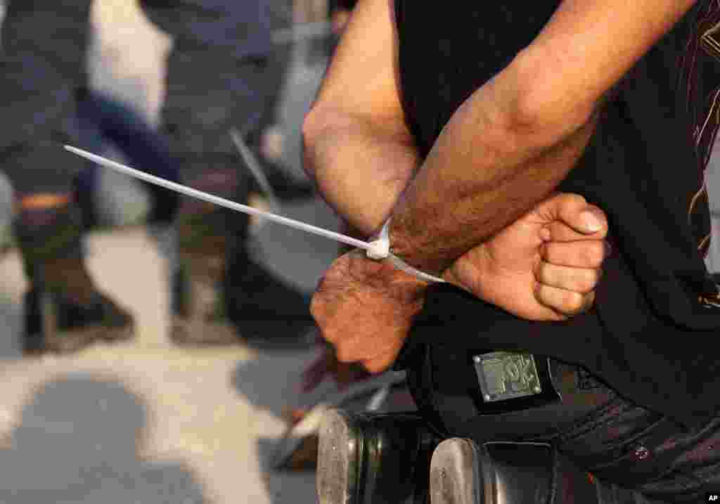 Bahraini man is seen handcuffed beside a road in Manama as police stop motorists entering the capital, checking identification and detaining young men from several cars. (AP)