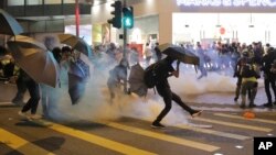 Seorang demonstran menendang kaleng gas air mata dalam bentrokan antara demonstran dengan polisi di Hong Kong, Minggu (10/11). 