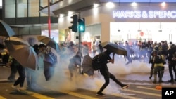 A protestor kicks away a police teargas shell as they clash outside a shopping mall in Hong Kong, Nov. 10, 2019.