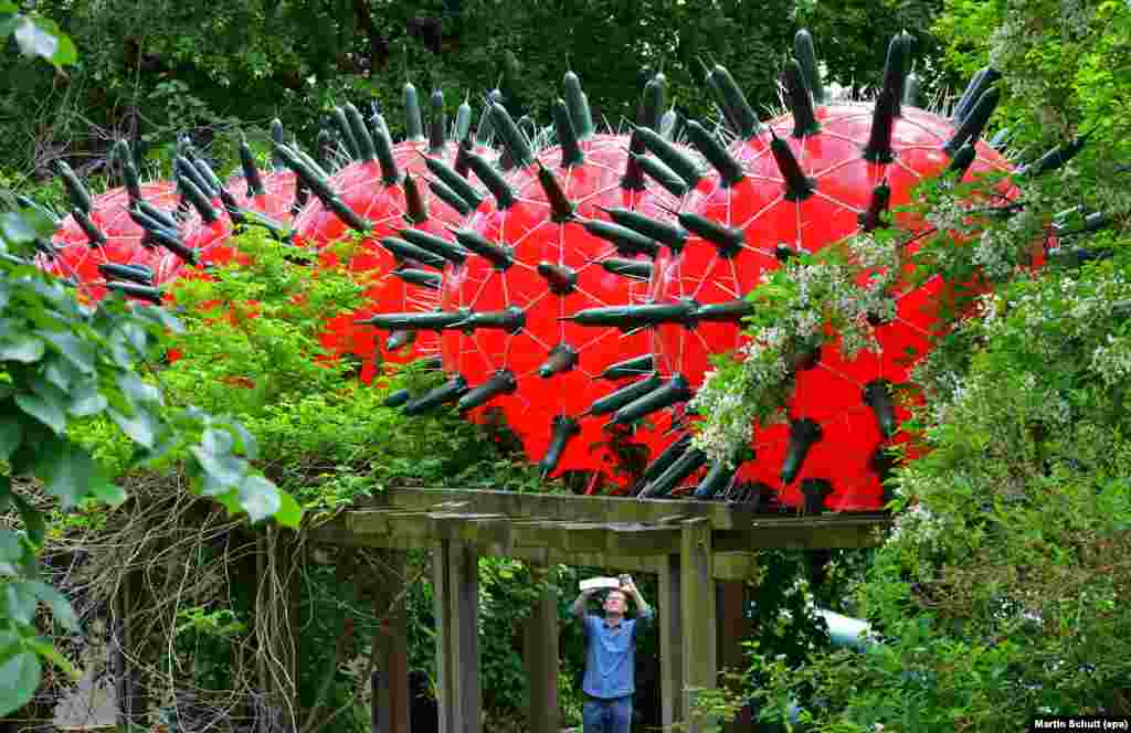 A man takes a picture of the art installation &#39;Visitors&#39; by artist Andre Tempel from Dresden at the Frommannsche Skulpturen garden in Jena, Germany.