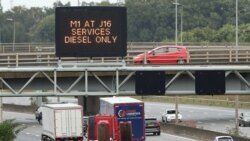 Trucks drive past a fuel warning sign on the M1 motorway amid a fuel shortage, in Luton, England, Sept. 30, 2021.