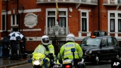 FILE - Police motorcyclists briefly stop outside the Ecuadorian embassy in London, Feb. 13, 2018.