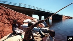 Des enfants font la pèche à côté d’un pont, sur le fleuve Limpopo, près de Xai Xai, Mozambique, 2 décembre 2000.