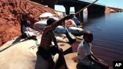 Des enfants font la pèche à côté d’un pont, sur le fleuve Limpopo, près de Xai Xai, Mozambique, 2 décembre 2000.