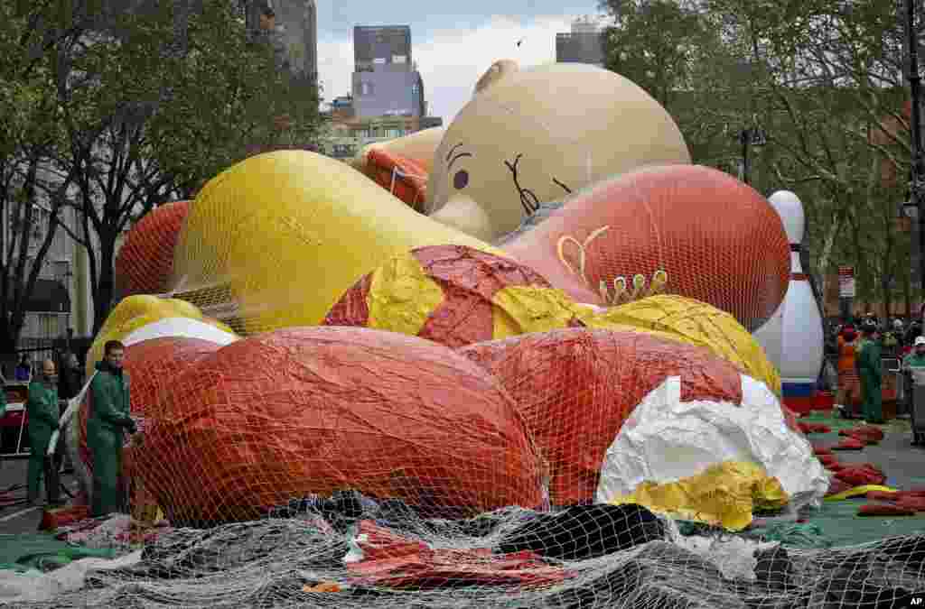 Globos de personajes gigantes, incluyendo a Charlie Brown, se alistan una noche antes del gran día. 