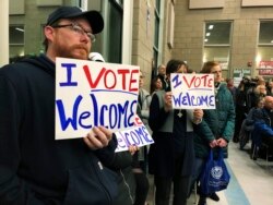 FILE - Residents in support of continued refugee resettlement hold signs at a meeting in Bismarck, North Dakota, Dec. 9. 2019.