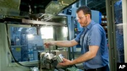 FILE — Brian Gasiewski, who received training at Macomb Community College, removes an external housing for an industrial shock absorber from a CNC machine at Fitzpatrick Manufacturing Co. in Sterling Heights, Michigan.