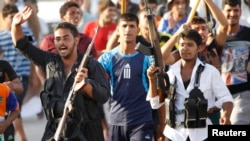 Volunteers, who have joined the Iraqi Army to fight against predominantly Sunni militants from the radical Islamic State of Iraq and the Levant (ISIL), carry weapons during a parade in the streets in Al-Fdhiliya district, eastern Baghdad June 15, 2014.