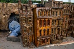 A man works around miniature brownstone buildings during the preparations for the annual Holiday Train Show at the New York Botanical Garden in New York, Nov. 11, 2021.